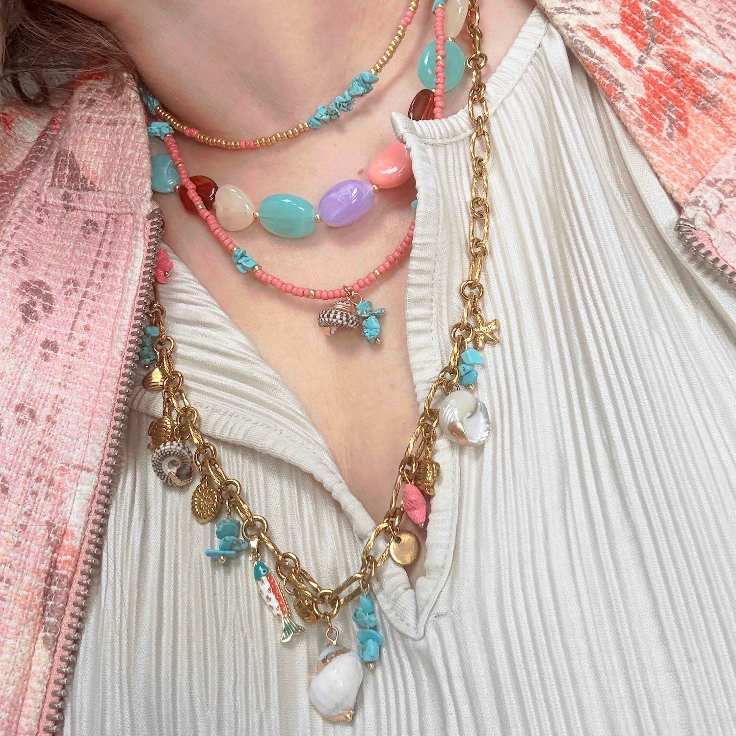 Gelaagde kralenketting met schelphanger, turquoise chips, zoetwaterparels en gouden zeebedels in koraalroze en pasteltinten.