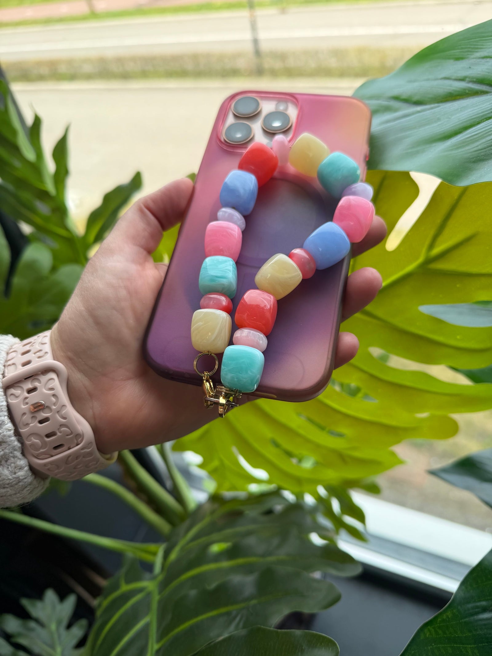 Kleurrijk telefoonkoord van acryl en resin kralen in roze, blauw, rood en mintgroen, geregen op een gouden schakelketting